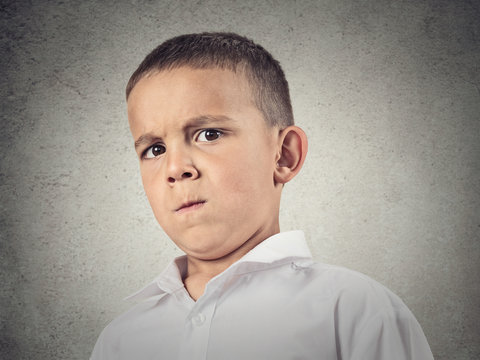 Suspicious boy, full of skepticism isolated grey wall background