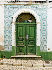 Antique door in a house with worn tiles wall.