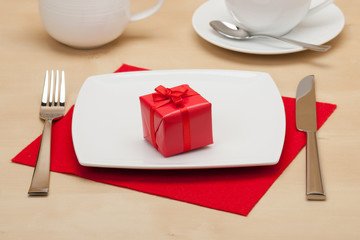 Red Gift Box On White Plate. Wooden Table