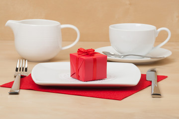 Red Gift Box On White Plate. Wooden Table