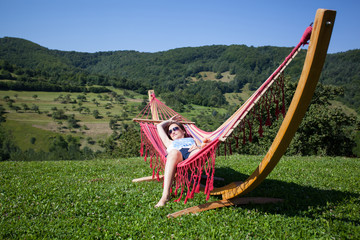 Obraz na płótnie Canvas Young female relaxing in a hammock