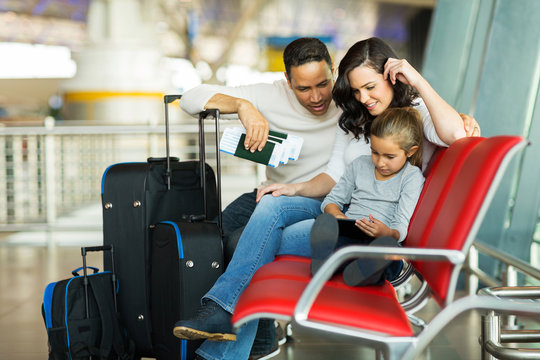 young girl with parents using tablet computer at airport