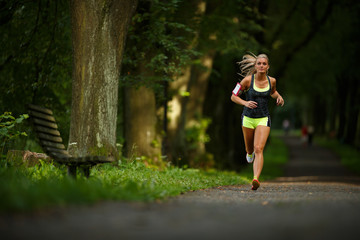 Obraz na płótnie Canvas Young lady running. Woman runner running through the spring park