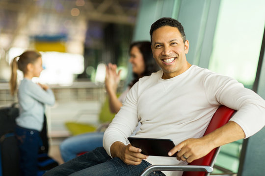 man holding tablet computer at airport waiting for flight with f