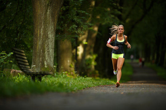 Young lady running. Woman runner running through the spring park