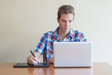 young adult using computer and touch input tablet