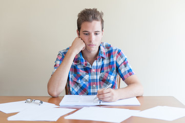 Young adult studying ,feeling frustrated, in a messy desktop