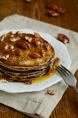 Stack of homemade thin pancakes topped with honey and pecan nuts