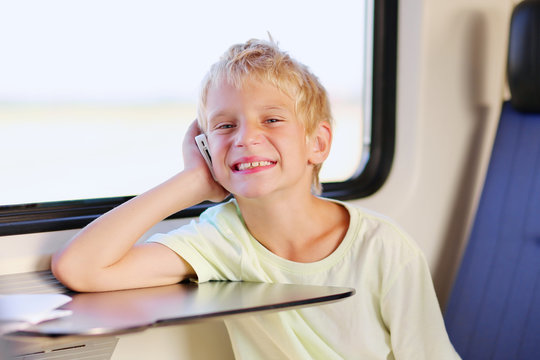 Young school boy talking on mobile phone sitting in train