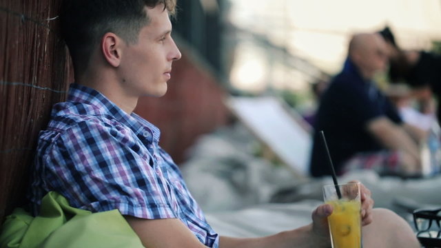 Young man drinking cocktail in trendy outdoor bar