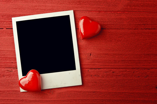 Blank photo and small red hearts on grunge background