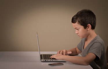 Little boy playing whith a computer and phone
