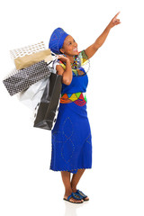 african woman with shopping bags pointing empty space