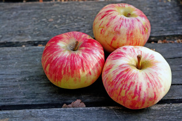 Three ripe apples on a rustic gray boards
