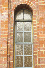 Ancient arched window with stained glass in brick wall