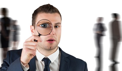 Composite image of businessman looking through magnifying glass