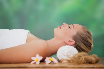 Obraz na płótnie Canvas Peaceful blonde lying on bamboo mat with flowers