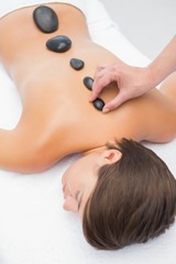 Obraz na płótnie Canvas Beautiful woman receiving stone massage at spa center