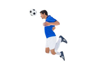 Fototapeta na wymiar Football player in blue jumping to ball