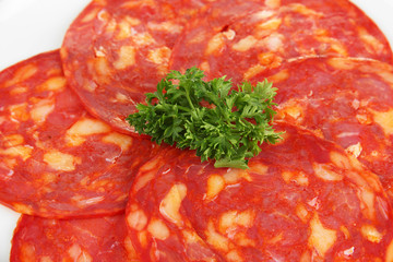 Salami slices on white plate, isolated on white