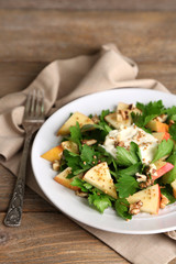 Green salad with apples, walnuts and cheese on wooden