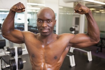 Fototapeta na wymiar Shirtless muscular man flexing muscles in gym