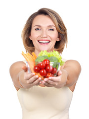 Portrait of a young smiling woman with a plate of vegetables.