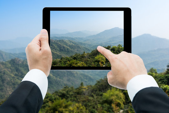 Businessman hands tablet taking pictures Mountains and blue sky