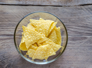 Heap of corn chips in the glass bowl on the wooden background