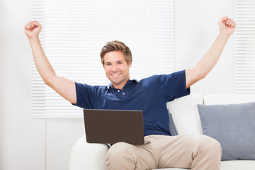 Excited Man With Laptop Raising Hands