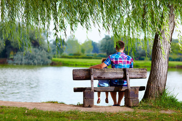 Naklejka na ściany i meble father and son sitting on the bench near the lake