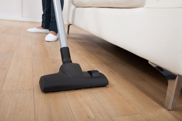 Low Section Of Woman Vacuuming Floor