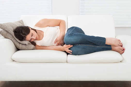 Woman Suffering From Stomachache On Sofa