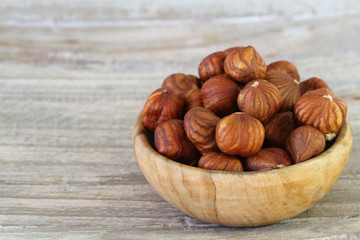 Hazelnuts without shell in wooden bowl with copy space