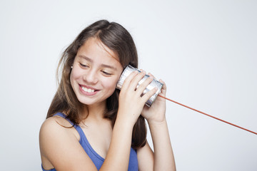 Happy smiling child using a can as telephone against gray backgr