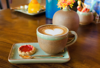 Cup of coffee, heart shape with strawberry biscuit on wood