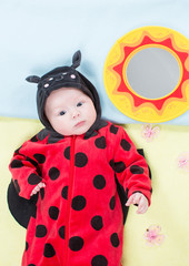 Pretty baby girl, dressed in ladybug costume on green background