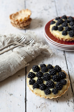 two homemade blackberries tart with pastry cream on wooden table