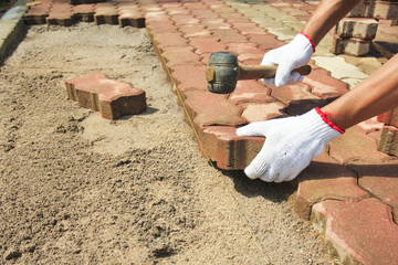 worker laying red concrete paving blocks.
