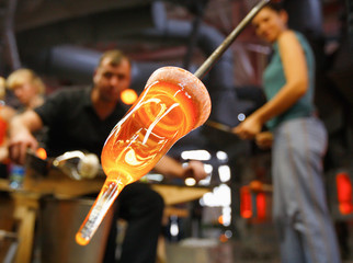 Glass furnace. Man holding a red-hot glass , close up