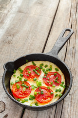 frying pan with scrambled eggs and tomatoes