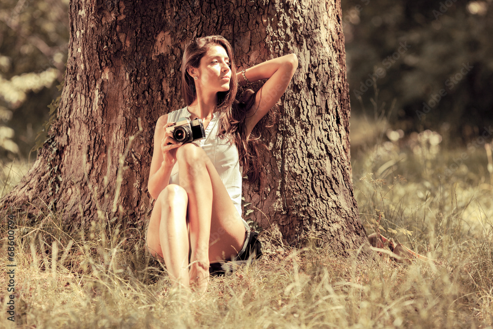 Wall mural Attractive female relaxing in nature.Holding camera.