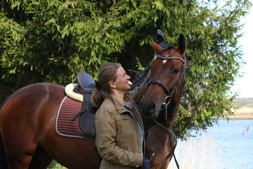 Young woman and brown horse together in the forest