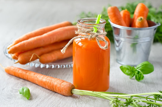 Freshly squeezed carrot juice in a glass and vegetables beside