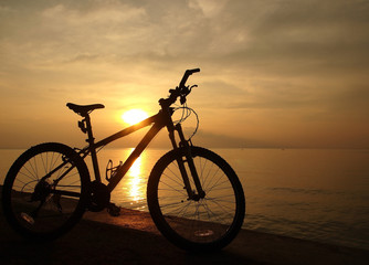 Fototapeta na wymiar Silhouette bicycle beside sunset sea