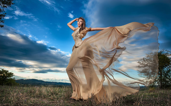 Fashionable beautiful young woman against cloudy sky