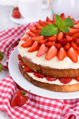 Delicious biscuit cake with strawberries on table close-up