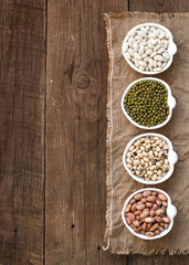 Assortment of legumes in bowls on wooden table