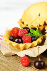 Tasty tartlets with berries on wooden table