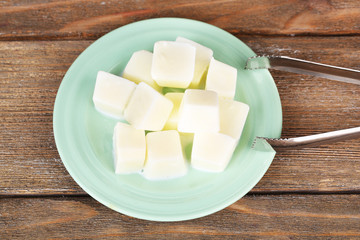 Milk ice cubes on plate on wooden background